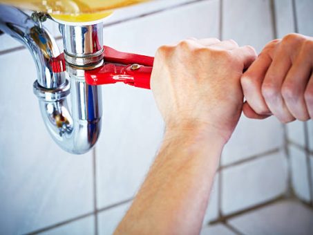 Plumber hands holding wrench and fixing a sink in bathroom
